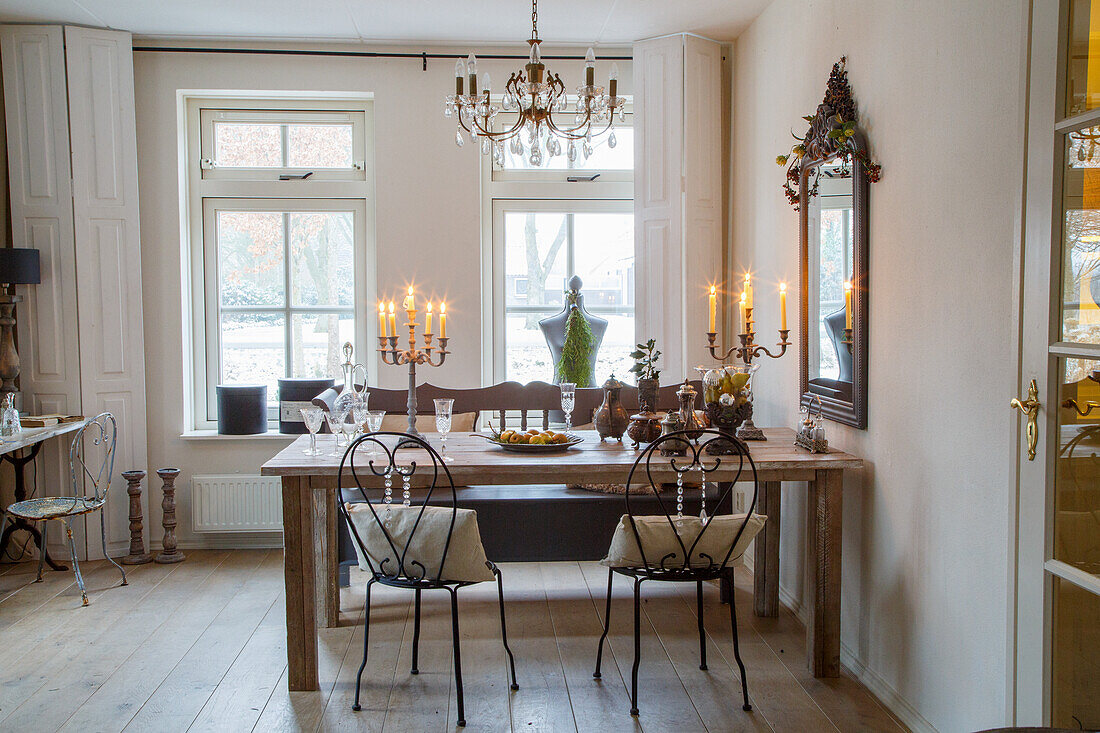 Dining room with wooden table and wrought-iron chairs, candlesticks and chandelier