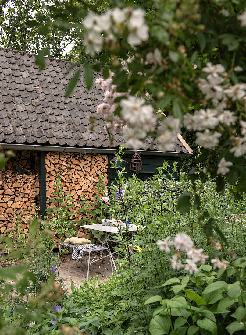 Sitzbereich umgeben von blühenden Sträuchern im Garten