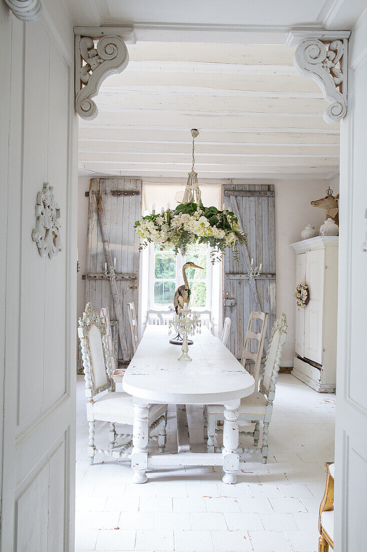 Shabby chic dining room with white wooden table and floral chandelier