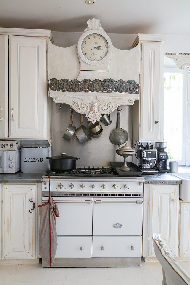 Antique kitchen clock above a white gas hob in a country kitchen