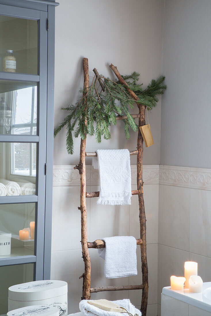 Rustic wooden ladder with fir branches and towels in the bathroom