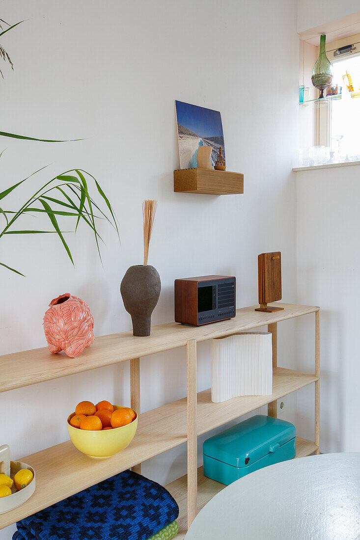 Wooden shelf with decorative objects, mandarins and a turquoise-coloured box in a bright room