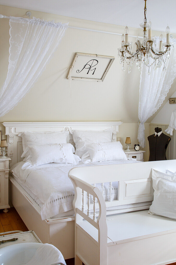 Schlafzimmer im hellen Landhausstil mit Himmelbett und Kronleuchter