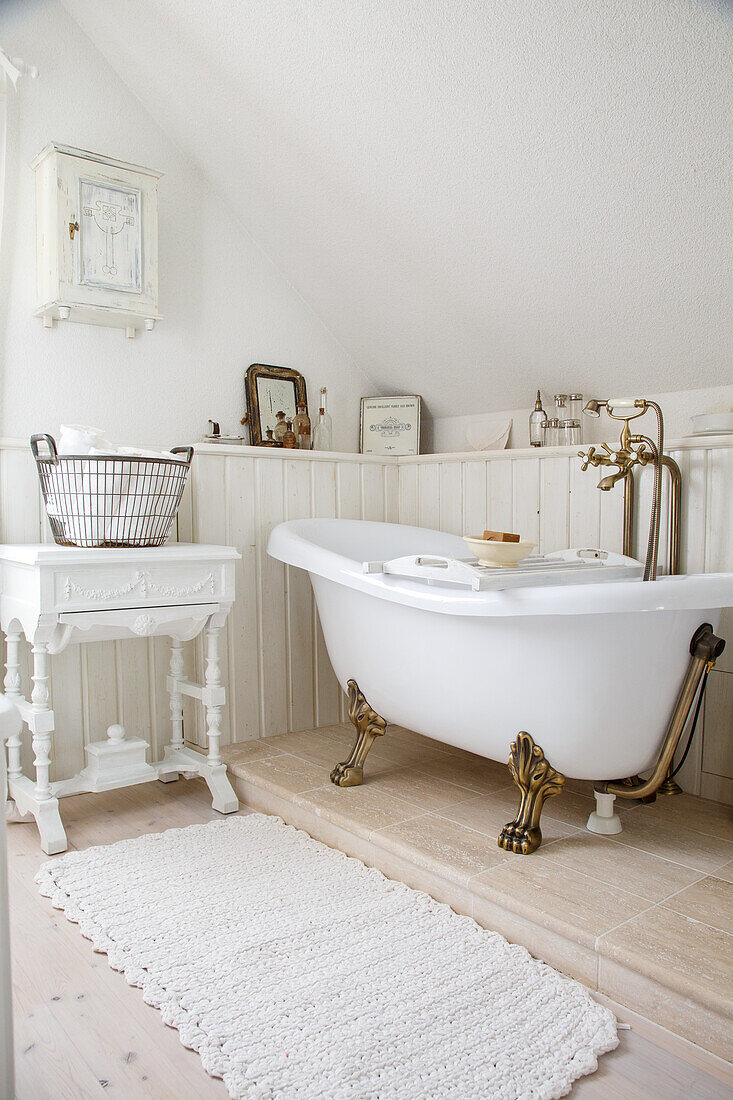 Freestanding vintage bathtub with golden lion feet in a white bathroom