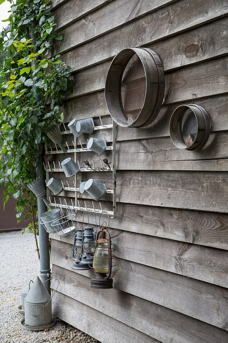 Wooden wall with metal pots, lanterns and sieves