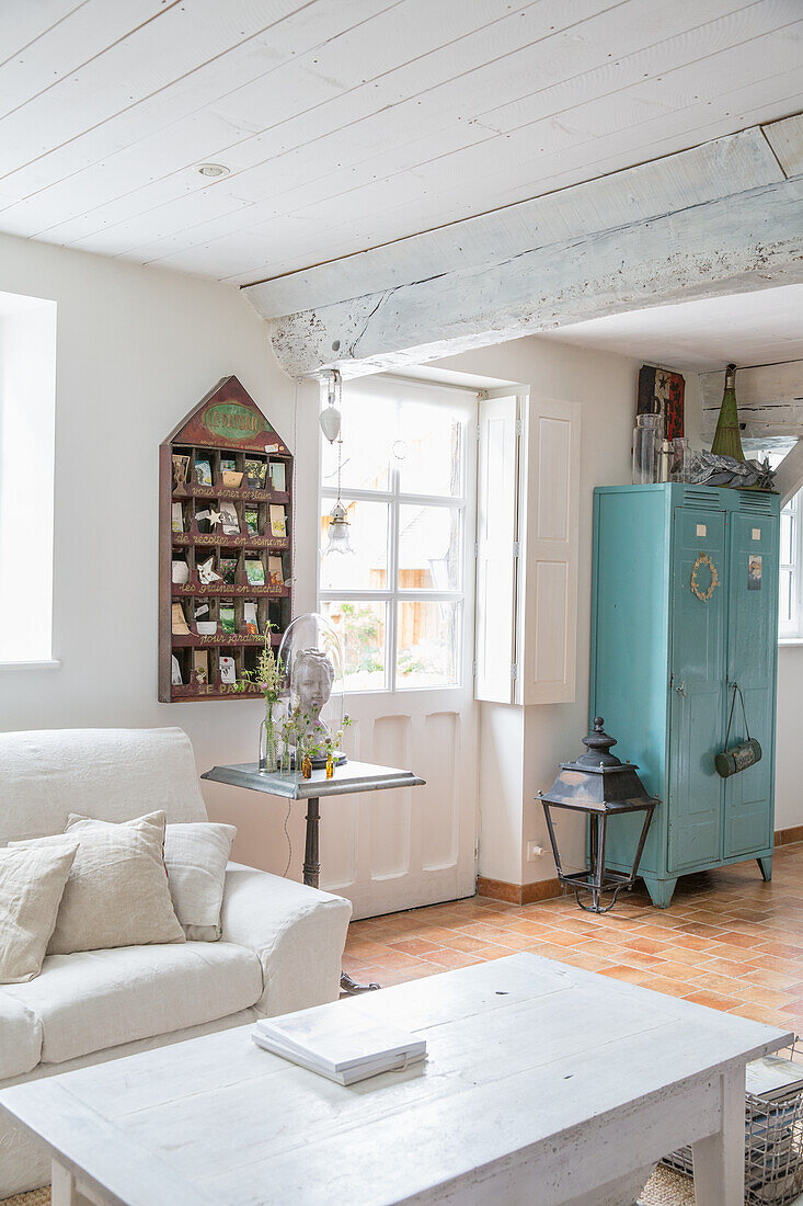 Bright country-style living room with blue metal cupboard and wooden beams