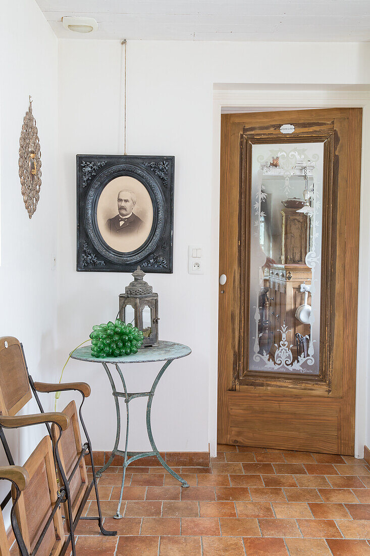 Entrance area with antique wooden chairs, metal table and historical portrait photo on the wall