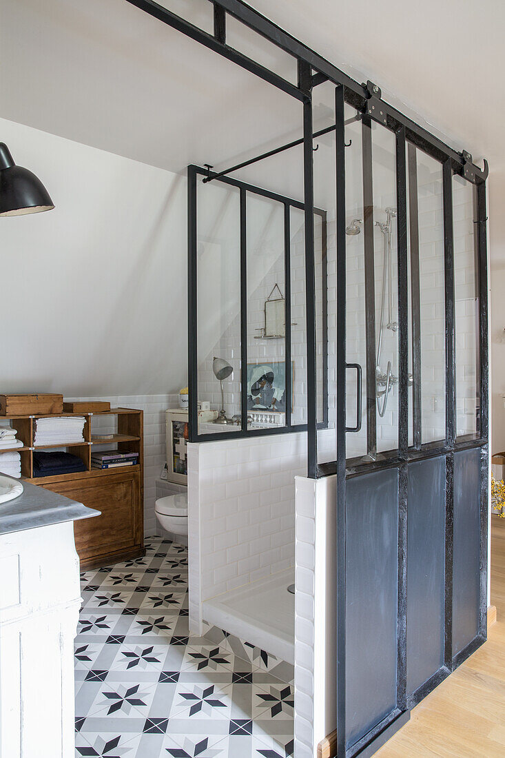 Bathroom with black and white patterned tiles and industrial-style glass shower enclosure