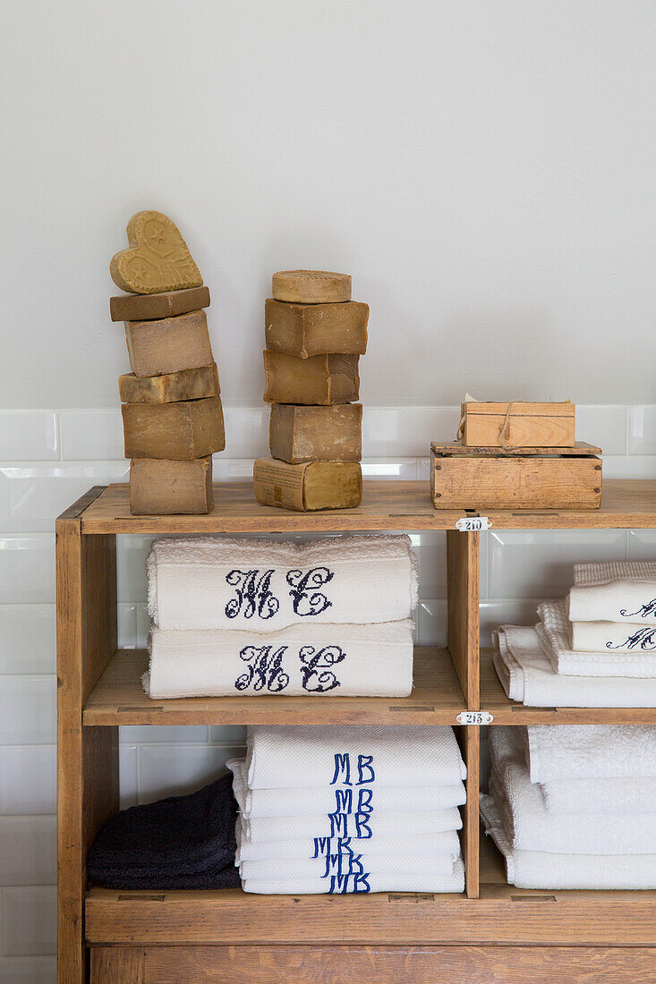 Stacked bars of soap and embroidered towels on a wooden shelf