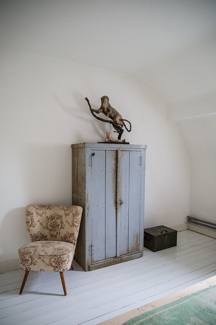 Blue-grey vintage cupboard and patterned retro armchair with stuffed animal