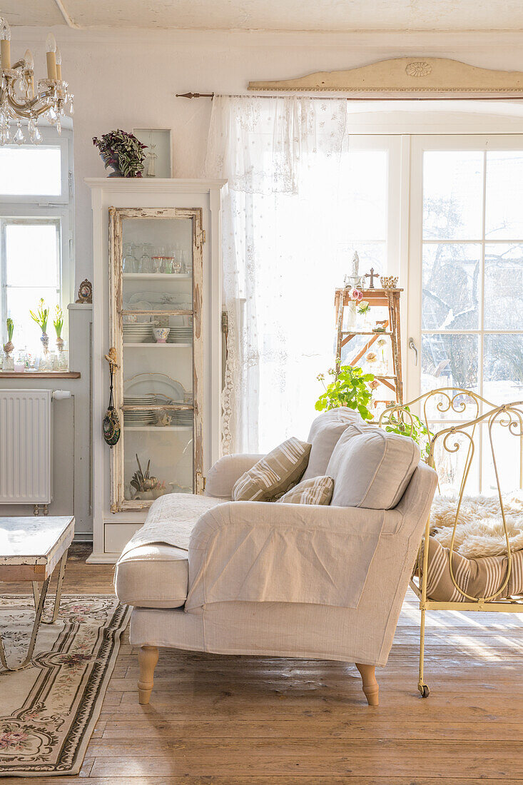 Sonnendurchflutetes Wohnzimmer mit Vintage-Vitrine und hellem Sofa