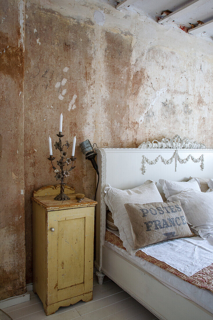 Bedroom with patina wall, antique bedside table and romantic bed