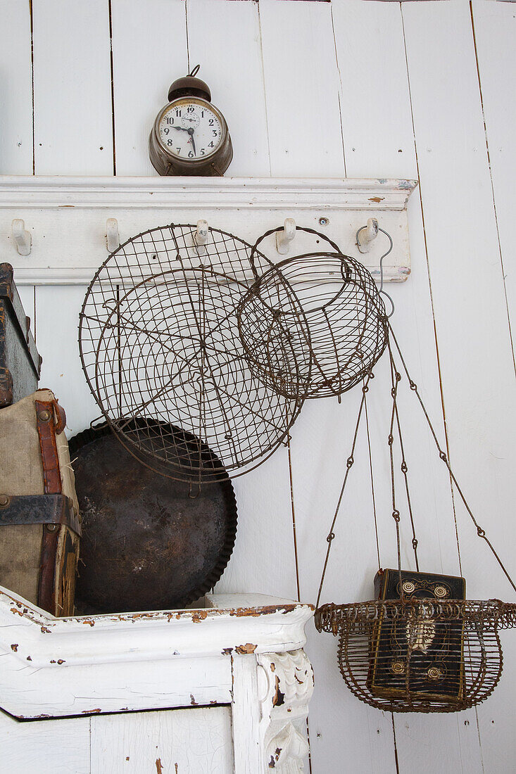 Vintage decoration with wire baskets and antique alarm clock on a white wooden wall