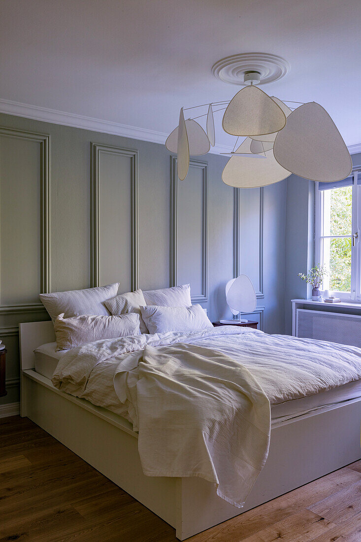 Bedroom with green-painted wood panelling, modern ceiling lamp and white bed