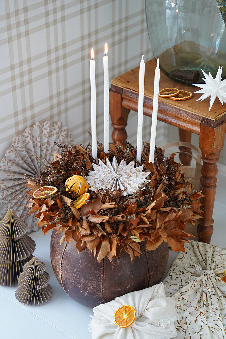 Advent arrangement made from dried leaves and origami stars with candles