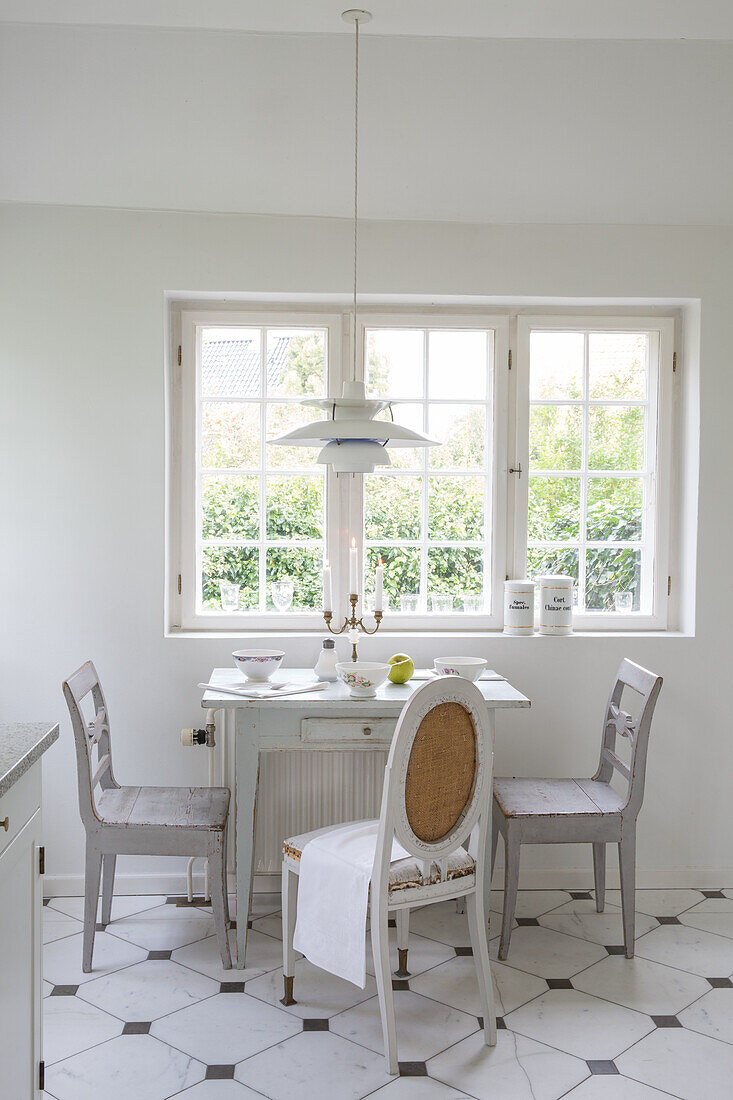 Small dining area with white country-style wooden furniture in front of the window