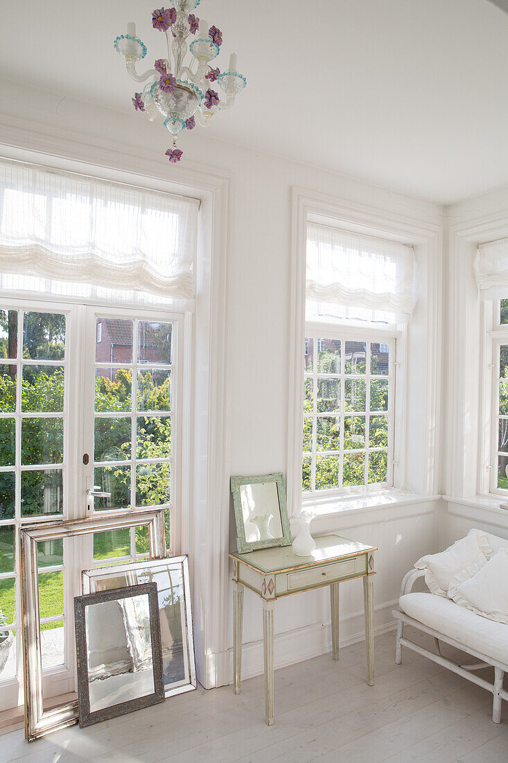 Light-flooded room with large windows and antique side table