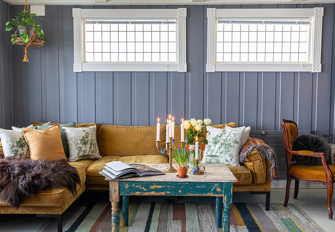 Living room with wood panelling, mustard yellow sofa and wooden table in a shabby chic look