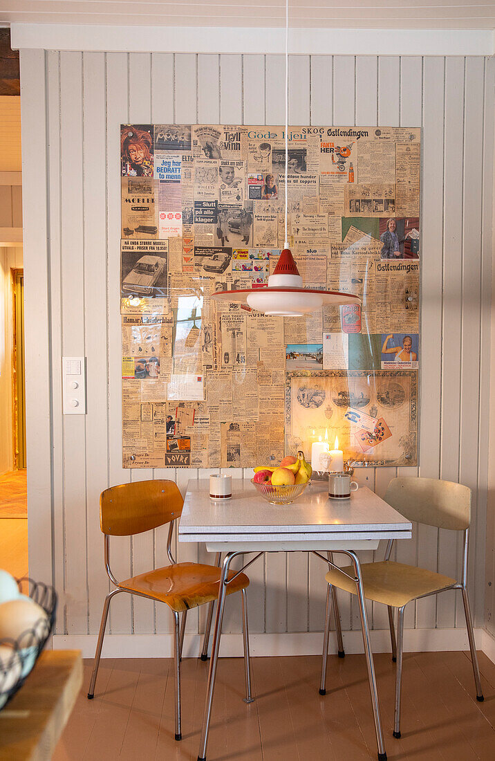 Küchentisch und Holzstühle mit Metallbeinen vor Wand mit Zeitungsdekor