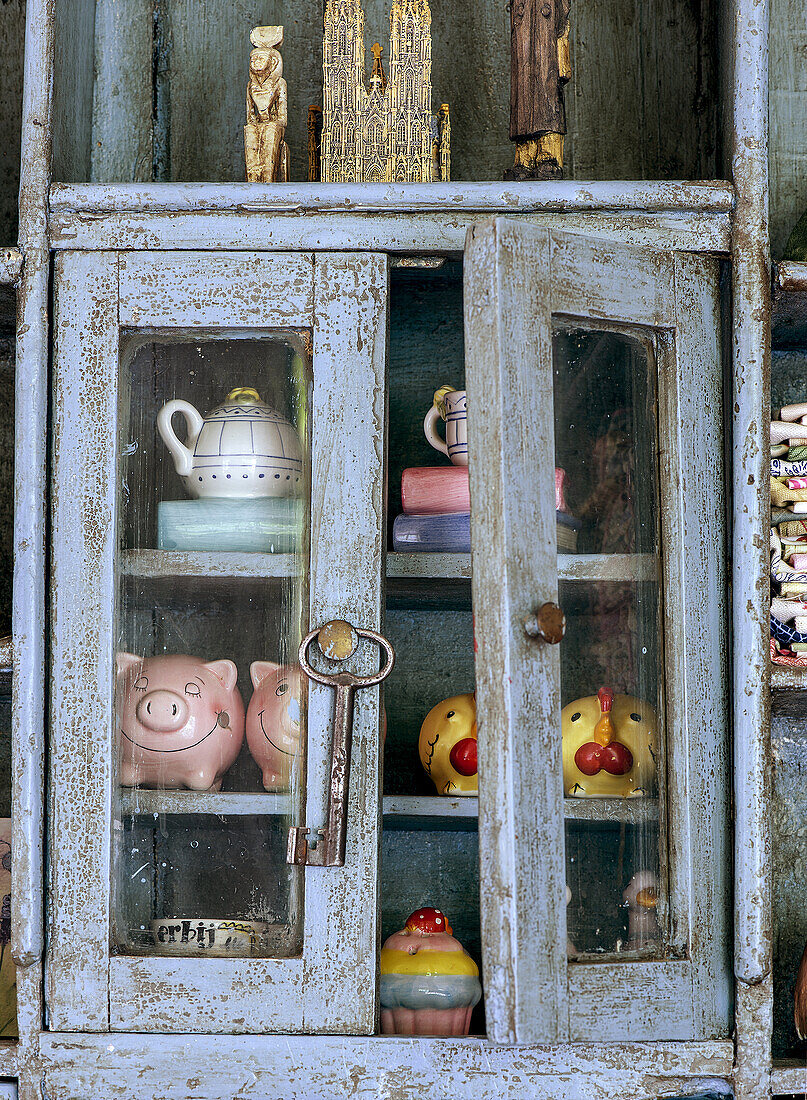 Antique wooden cabinet with key and colorful porcelain collectibles