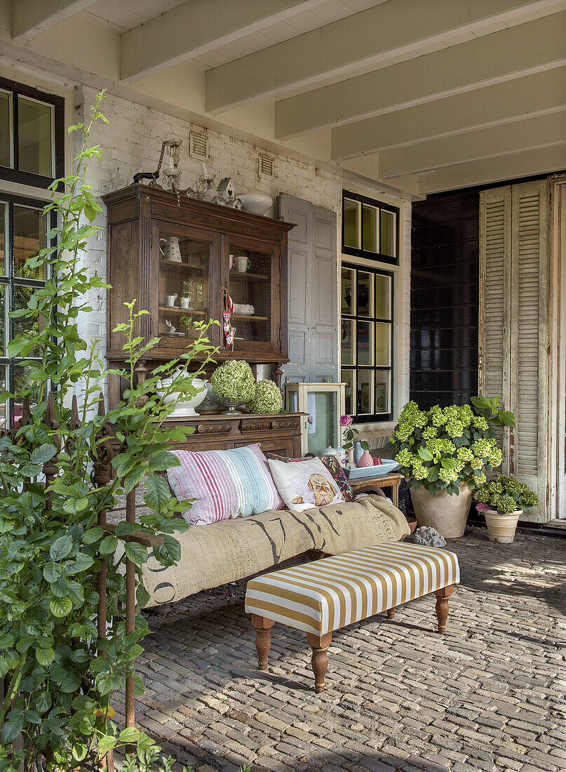 Überdachte Terrasse mit Vintage-Möbeln und Topfpflanzen