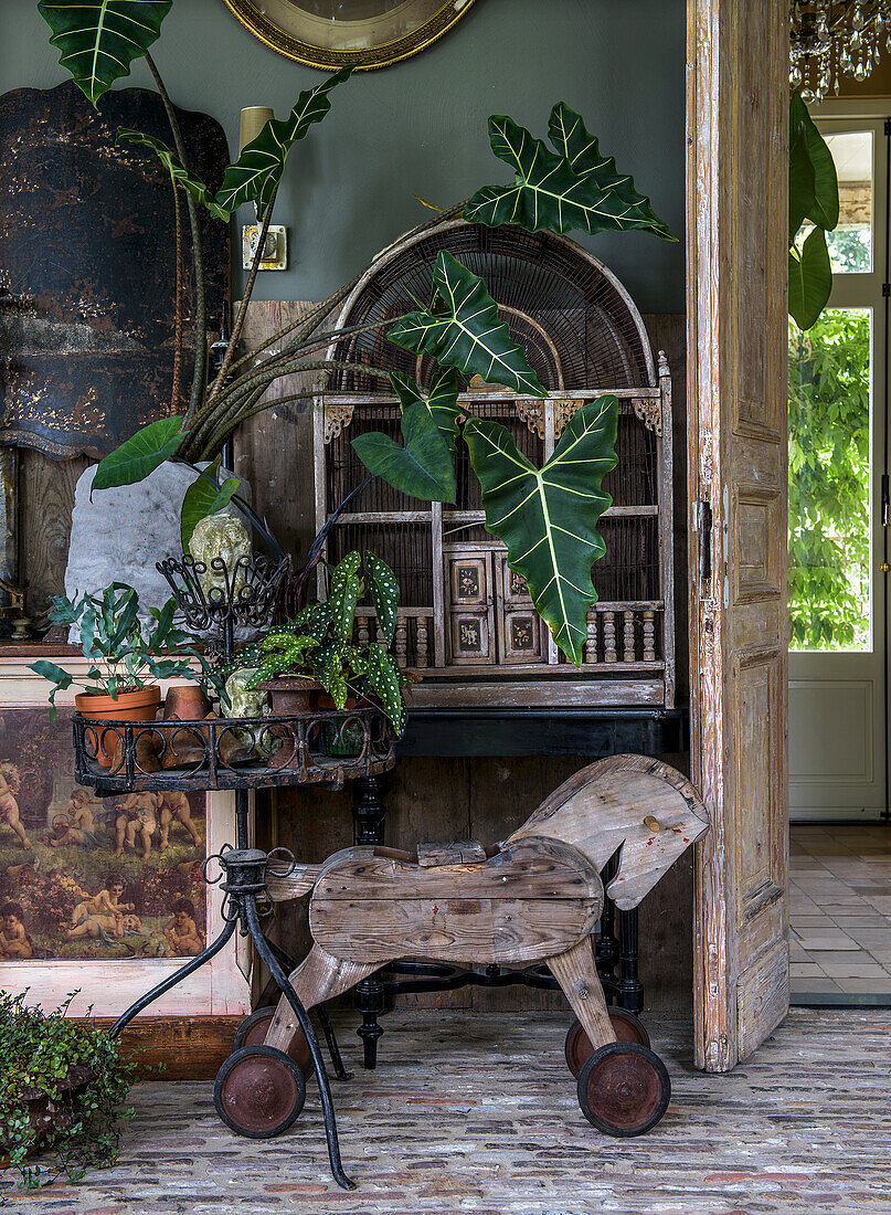 Rustic living area with wooden horse, plants and antique furniture