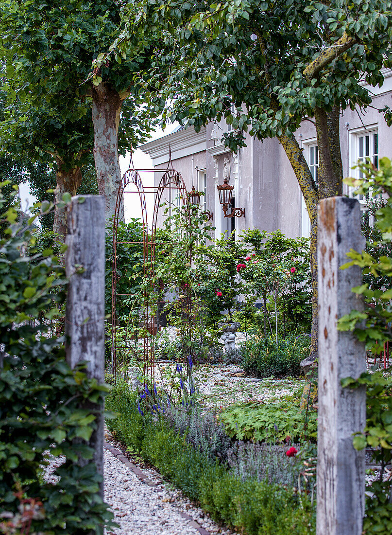 Malerisch bepflanzter Gartenweg mit Rosen und Rosenbogen