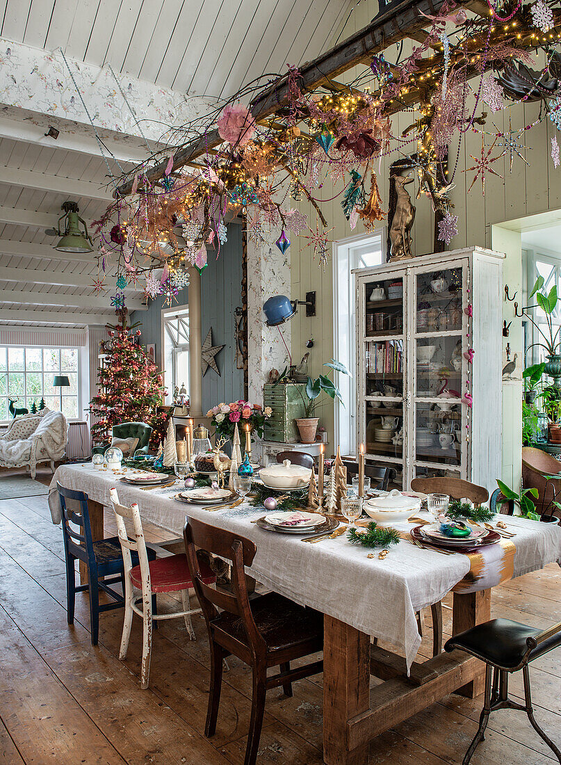 Festively laid dining table with rustic wooden furniture and Christmas decorations on a hanging ladder