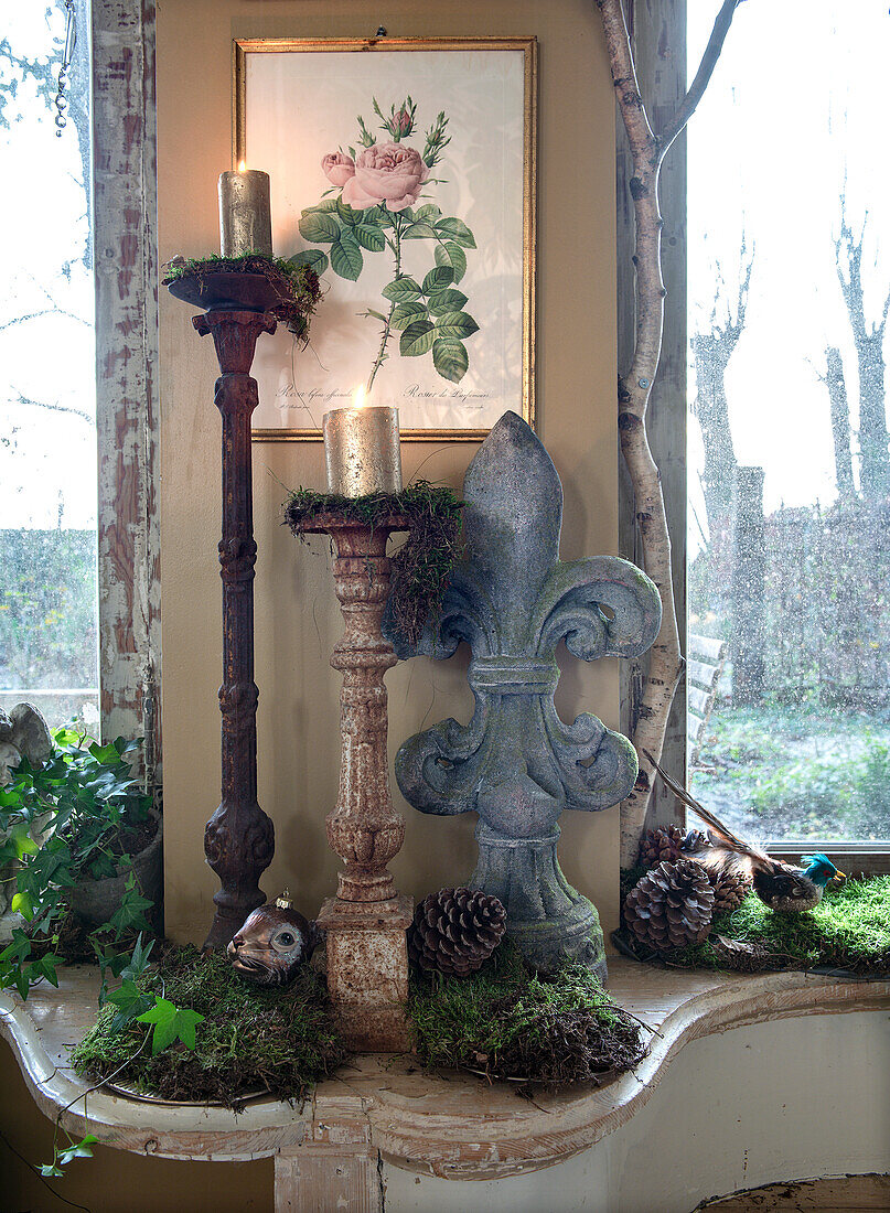 Windowsill decoration with candlesticks, moss and pine cones