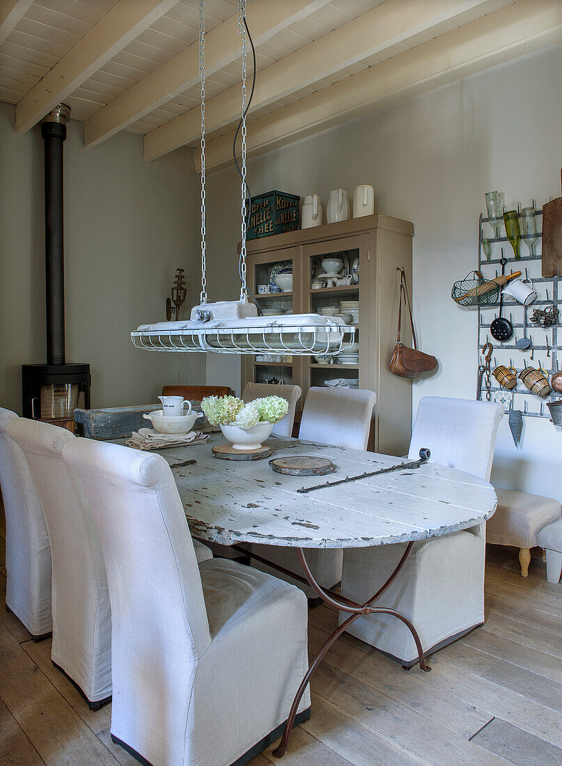 Dining room with rustic wooden table, fabric-covered chairs and wood-burning stove