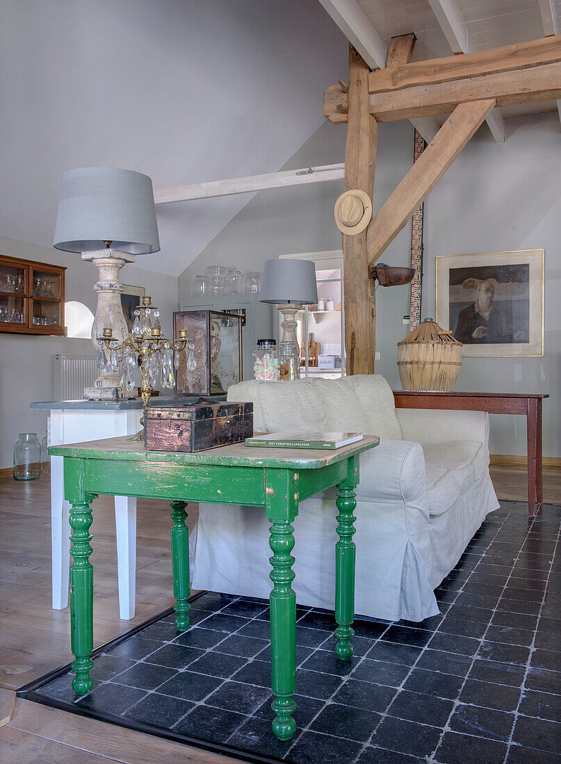 Rustic living room with green side table, white sofa and dark tiled floor