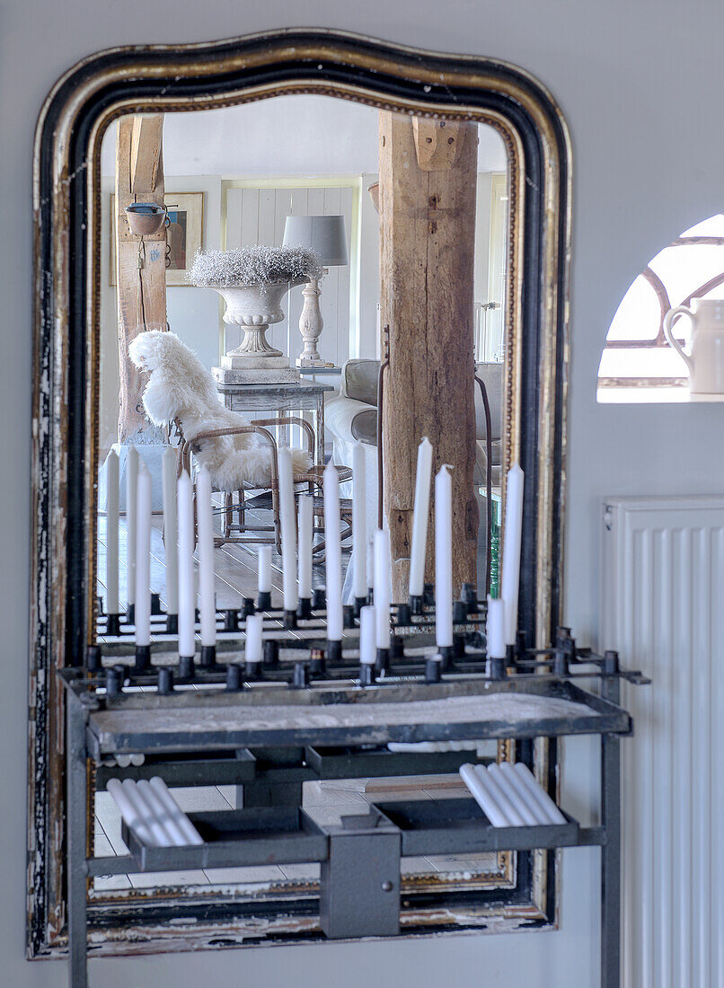 Large, antique mirror with candlesticks, reflecting rustic interior