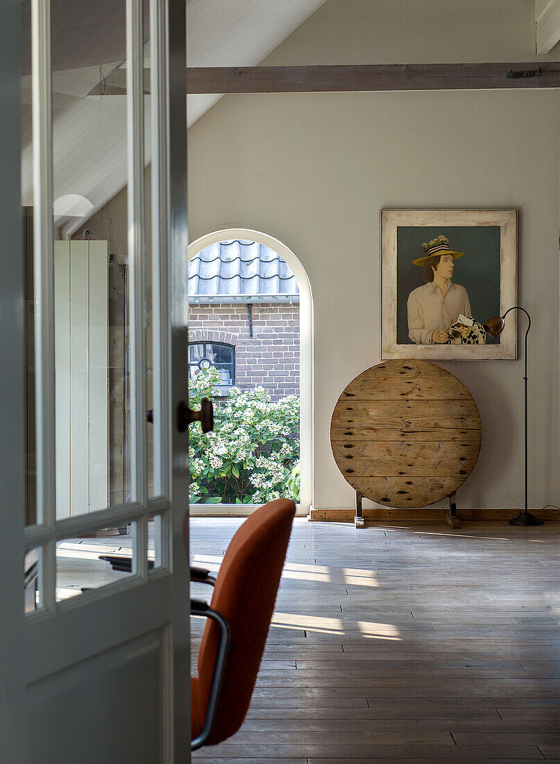 Open-plan living area with wooden floorboards, office chair and artwork on the wall