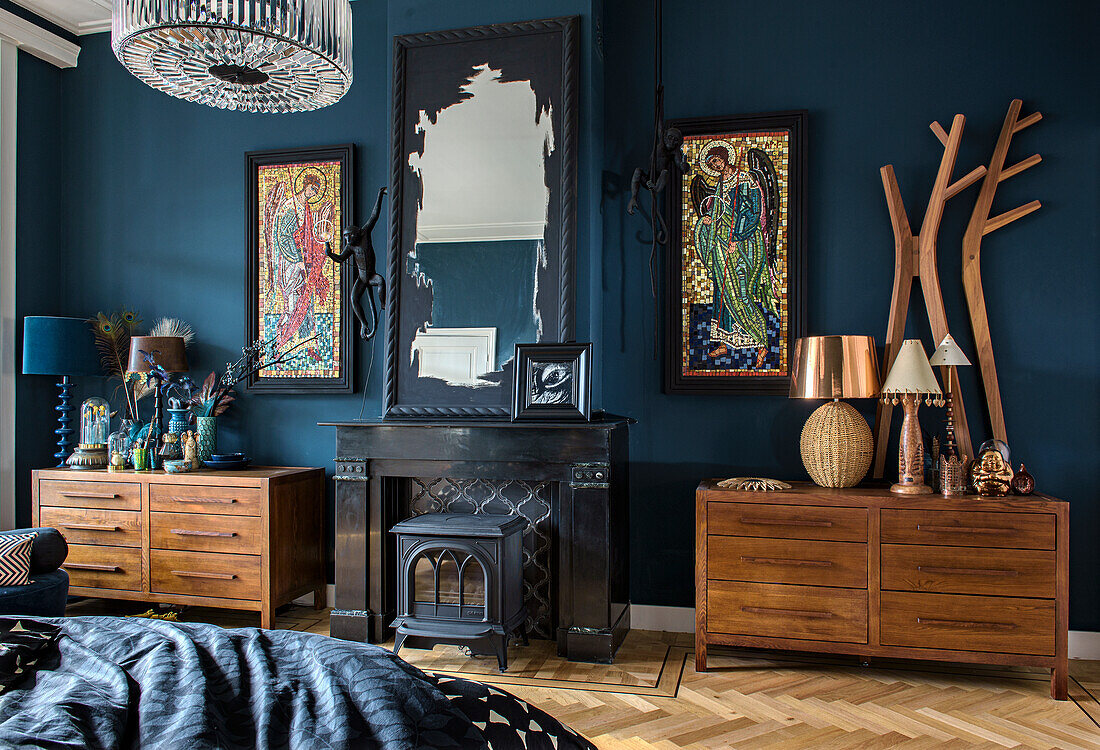 Fireplace and chests of drawers in bedroom with dark blue wall and herringbone parquet flooring