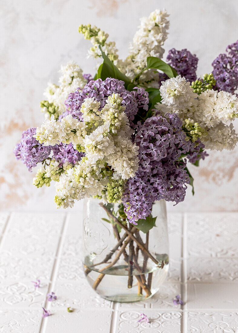 White and purple lilacs in a glass vase