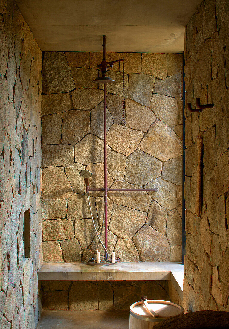 Dusche mit groben Steinfliesen und Betonbank in mexikanischem Badezimmer