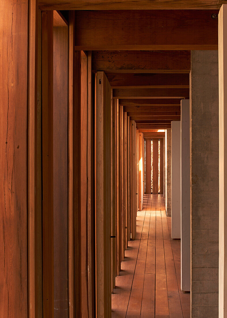 Wood-paneled hallway with exposed concrete columns in holiday home Casa Cometa