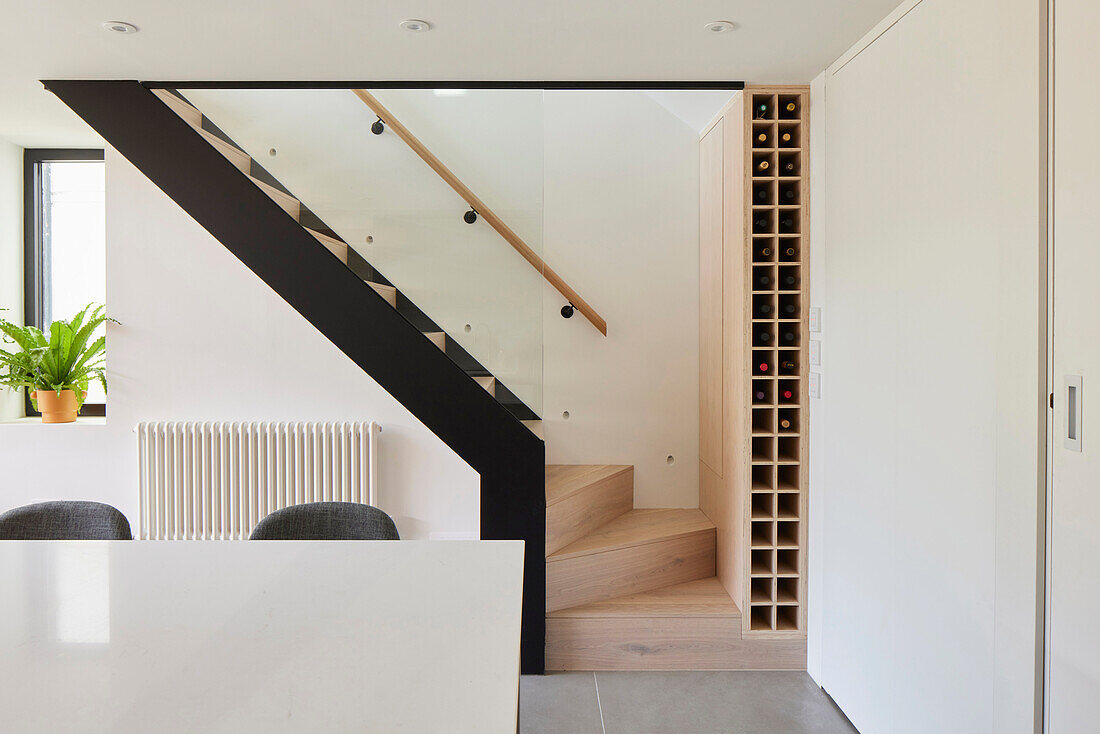 Modern kitchen with a view of the staircase, glass banister and integrated wine rack
