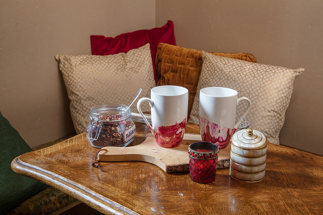 Teacups and tea in a preserving jar on an antique wooden table