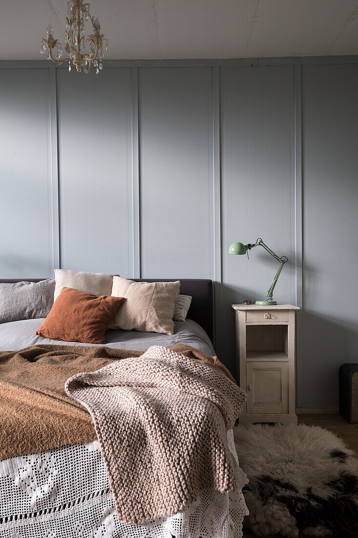 Schlafzimmer mit blaugrauer Wand, Wolldecke und grüner Leselampe