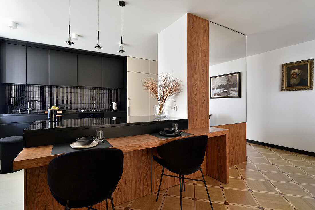 Modern kitchen with black cupboards and wooden table with black chairs, Warsaw, Poland