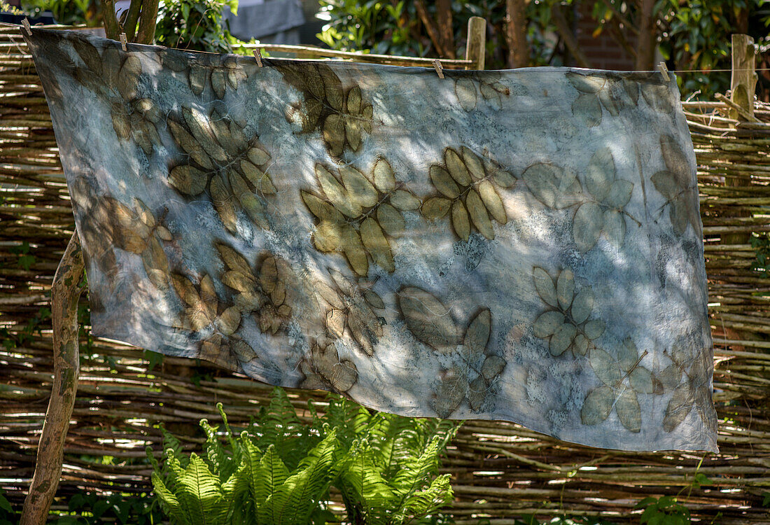 Coloured cloth with leaf pattern on fence in the garden