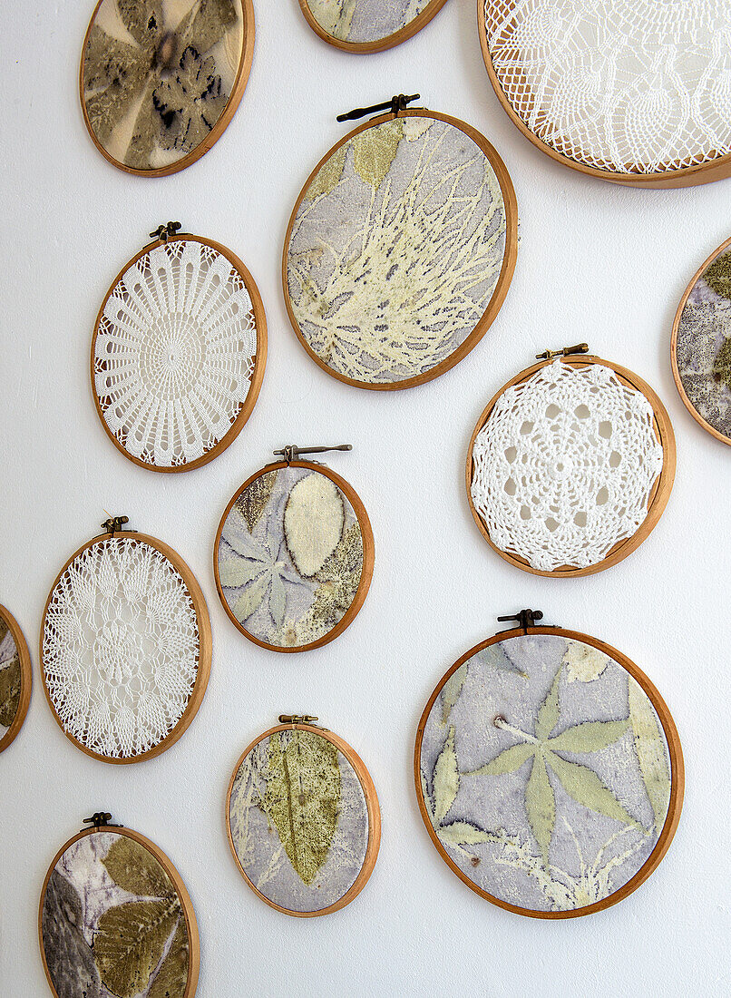 Embroidery hoop with pressed plants and crochet lace on white wall