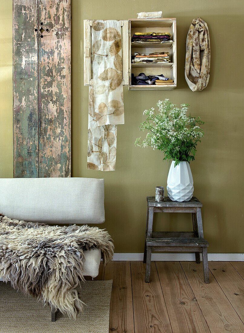 Living area inspired by natural colours and materials with fur, scarves and flower vase