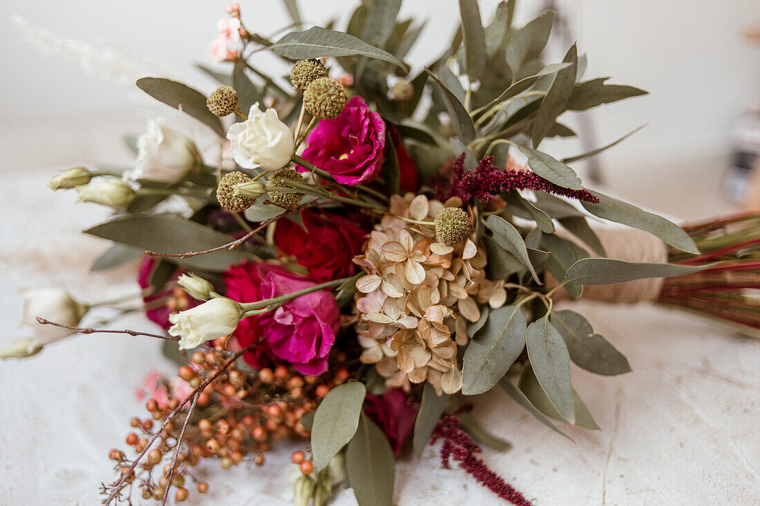 Brautstrauß mit Rosen und Eukalyptuszweigen auf Tischplatte