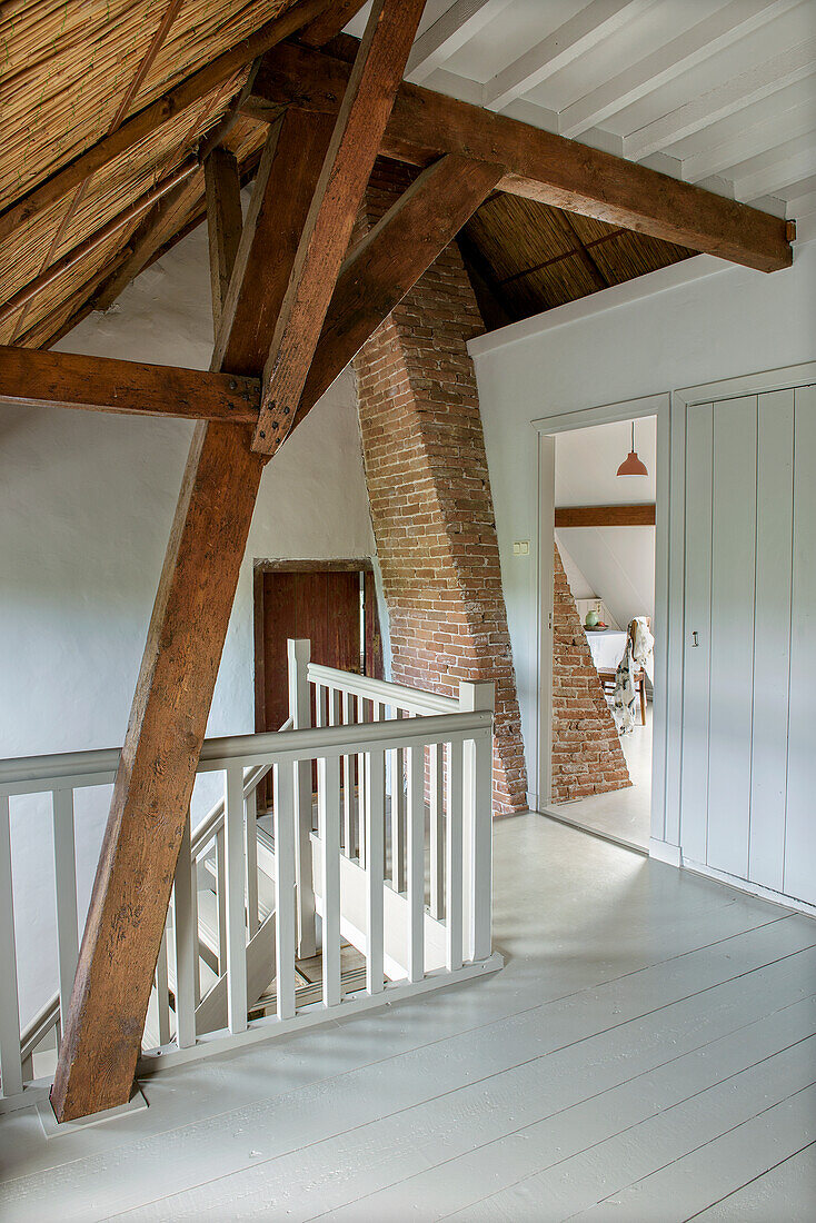 Hallway in the attic with exposed wooden beams and brick wall