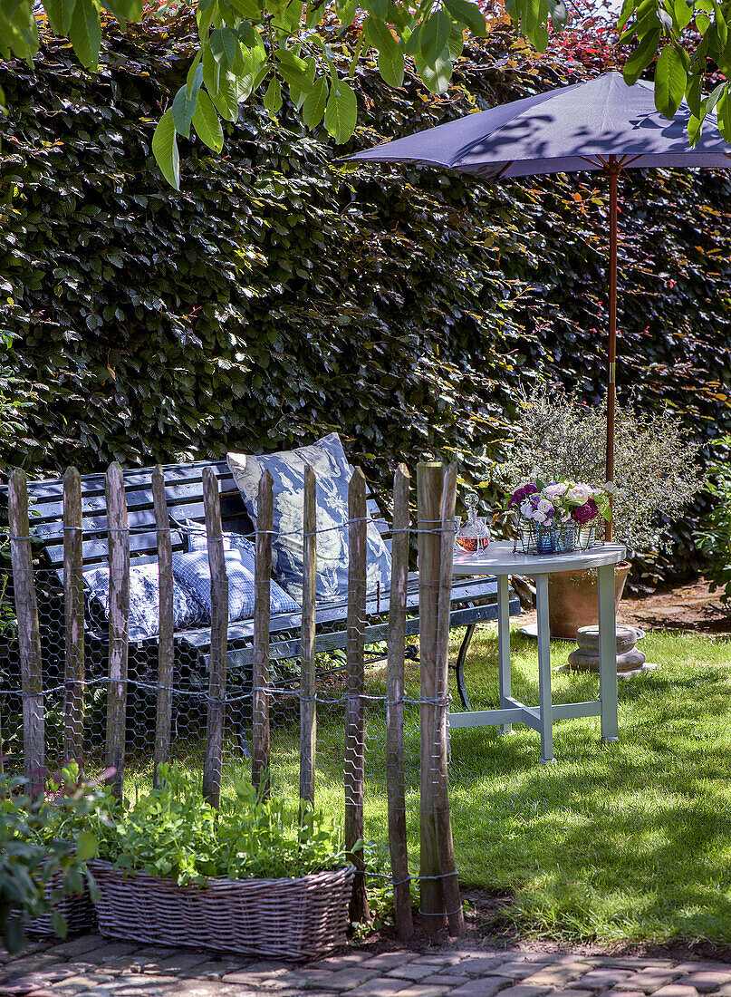 Wooden bench in shady garden corner with blooming flower arrangement