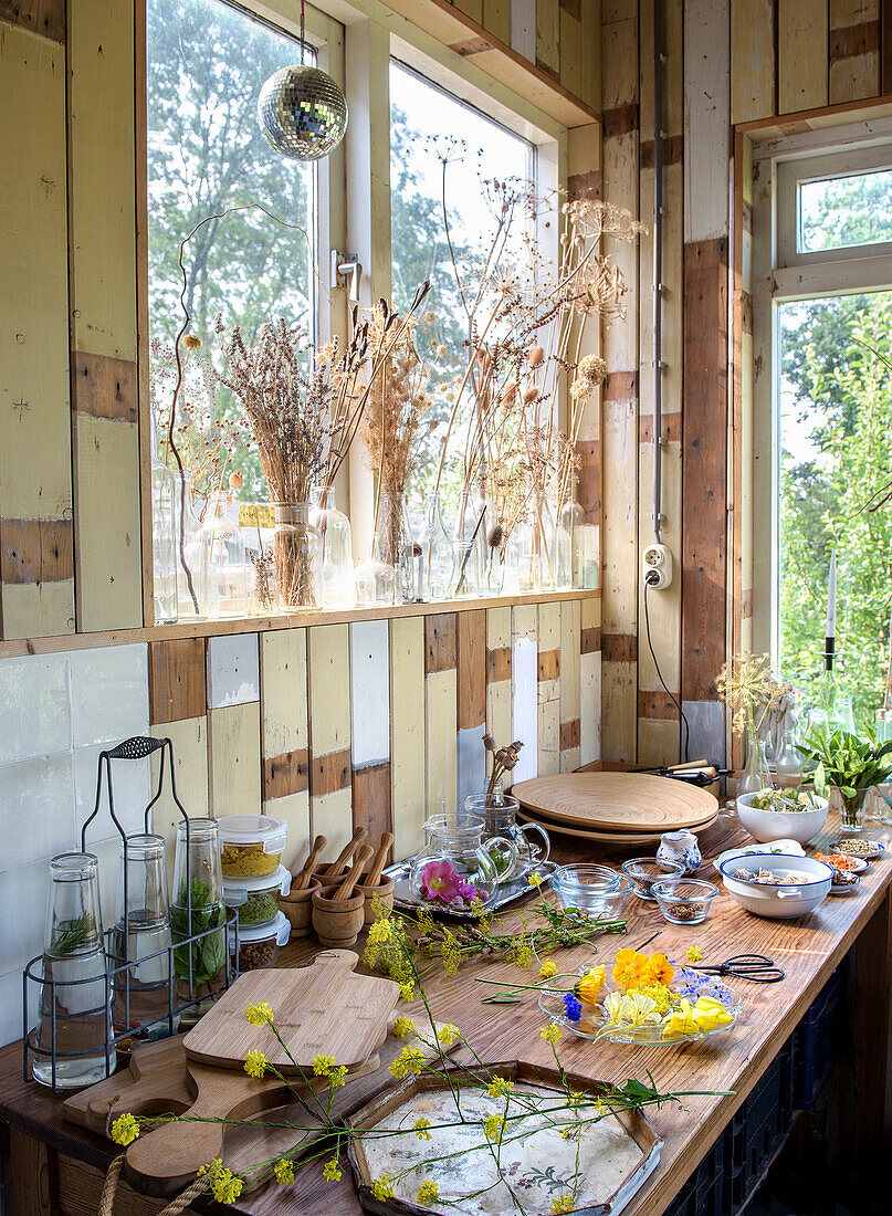 Wooden decor, blossoms and dried flower arrangement on windowsill in garden shed