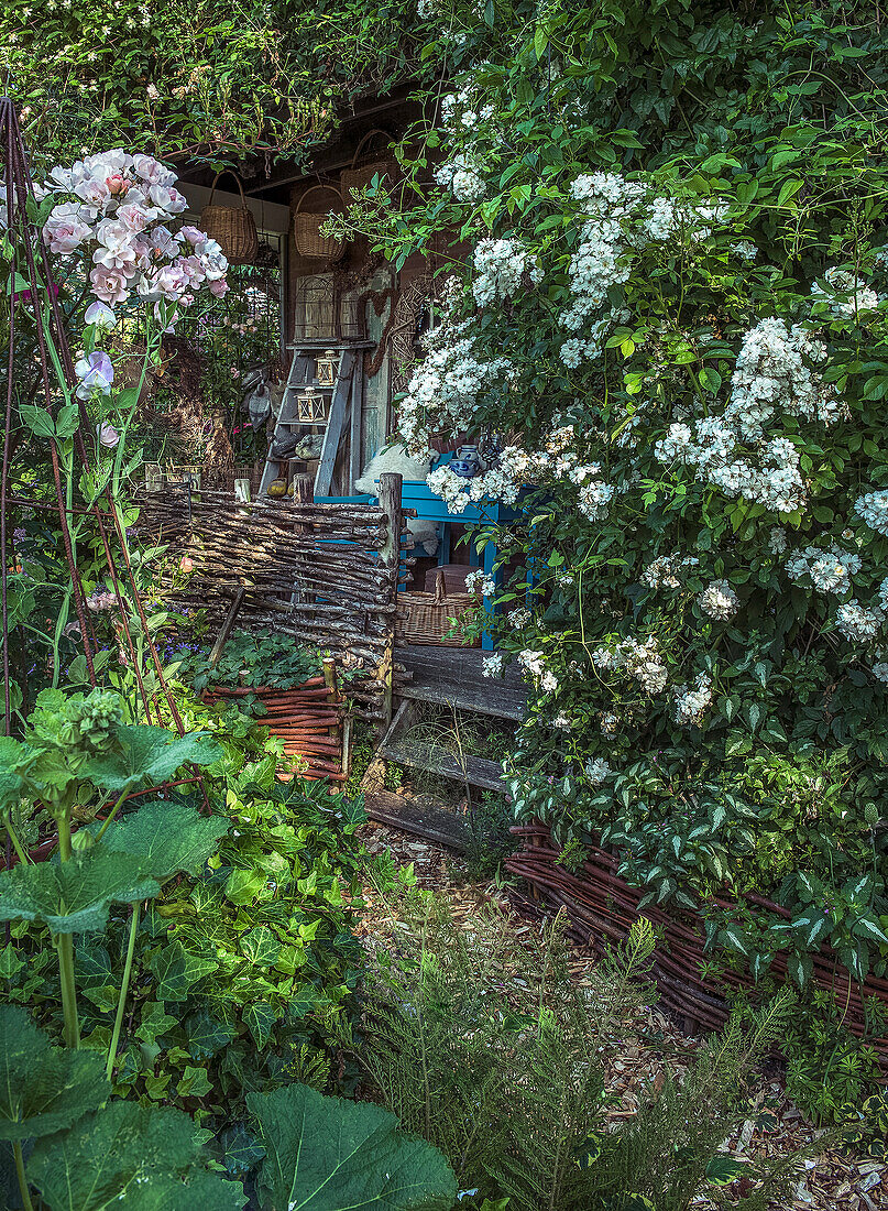 Idyllic gazebo with flowering shrubs and wattle fence