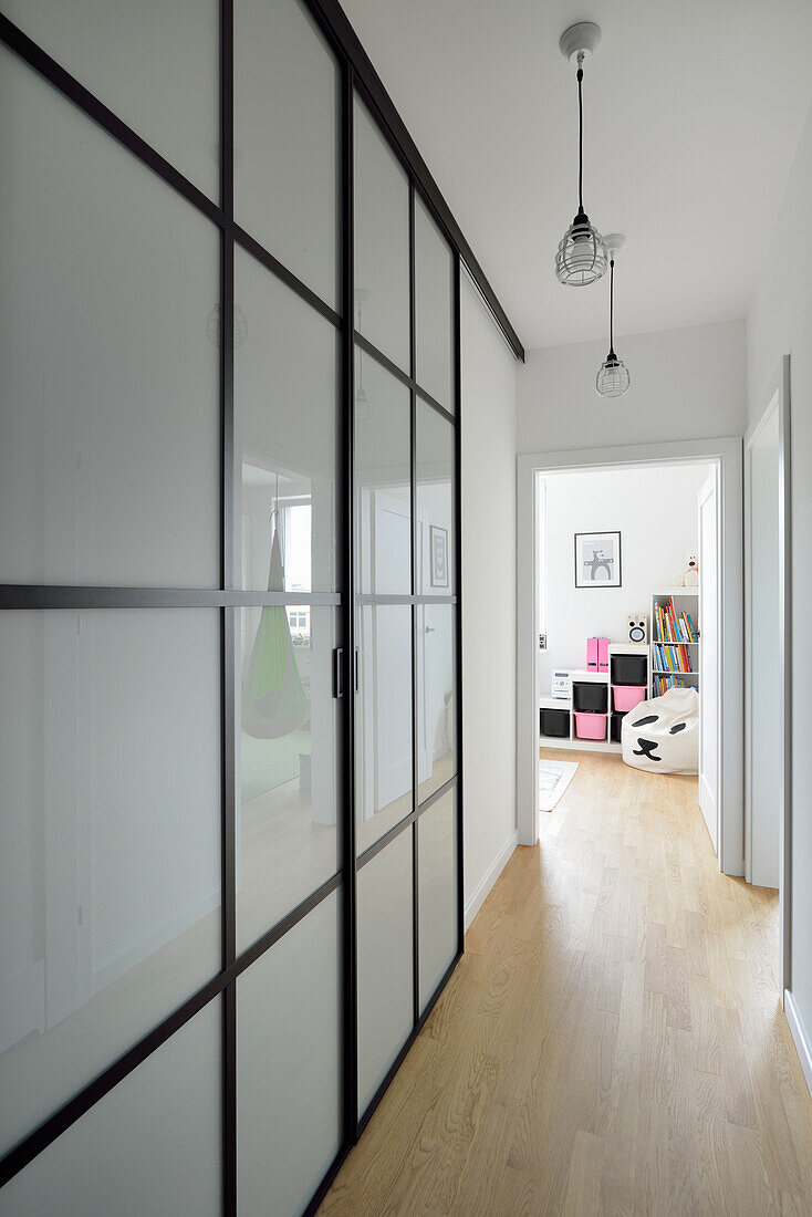 Hallway with glass doors and pendant light with view into children's room